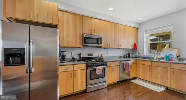 a kitchen with stainless steel appliances granite countertop a stove a sink dishwasher and a refrigerator with wooden floor