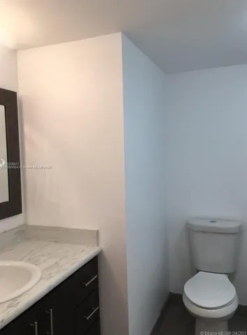a bathroom with a granite countertop toilet and a sink