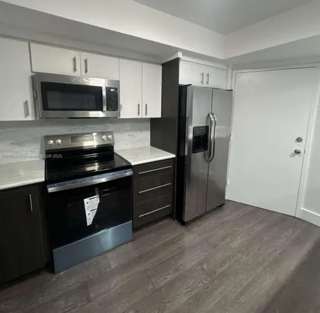 a kitchen with granite countertop a refrigerator and a stove top oven