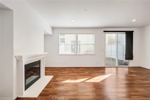 an empty room with wooden floor fireplace and windows