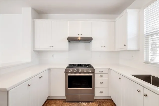 a kitchen with white cabinets and a stove with wooden floor