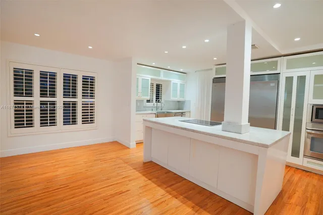 a large kitchen with granite countertop a large counter top space and stainless steel appliances
