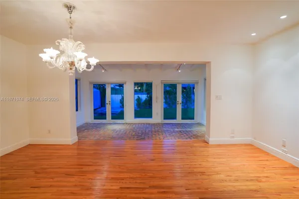 a view of an empty room with wooden floor and a chandelier