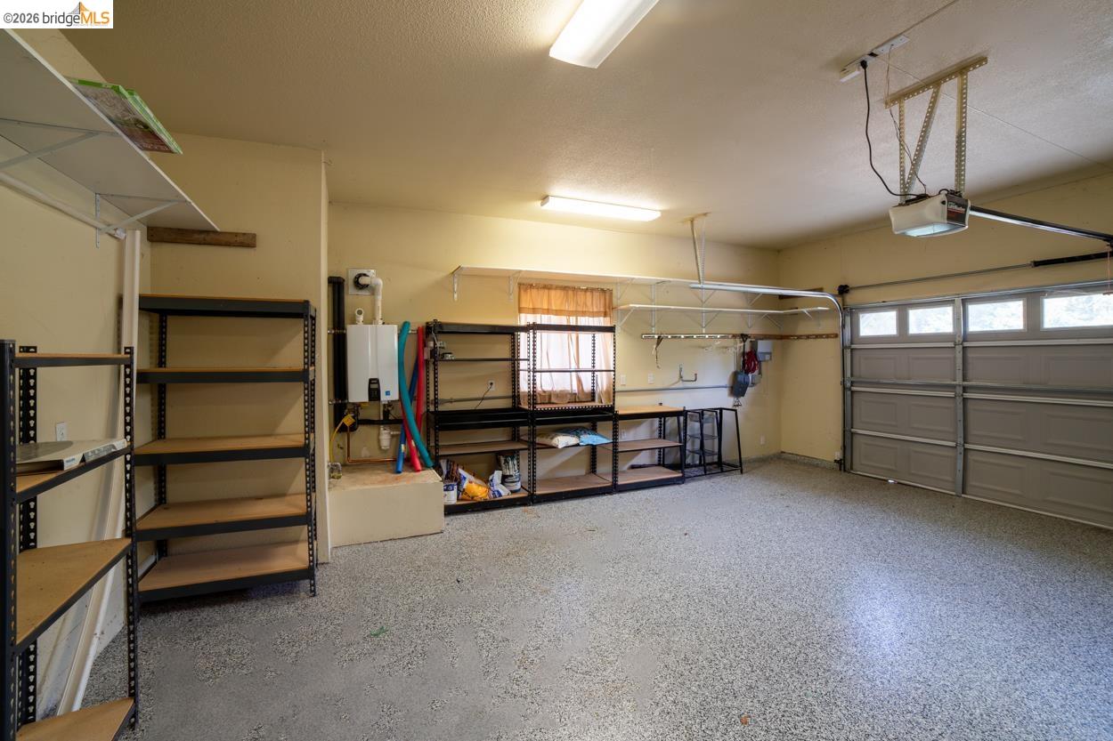 22401 Ridge Road Twain Harte, CA 95383 - Photo 32 of 52 Spacious garage featuring a durable epoxy-coated concrete floor, an overhead garage door, built-in shelving, and wall-mounted storage solutions