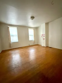 an empty room with wooden floor and windows in it