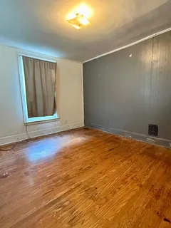 an empty room with wooden floor and windows with curtains