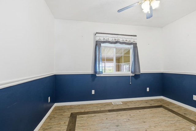 435 East 4th North Preston, ID 83263 - Photo 13 of 26 Interior room featuring a window with white trim, wood-finish flooring, a ceiling fan with light fixture, and two-tone wall paint with chair rail molding