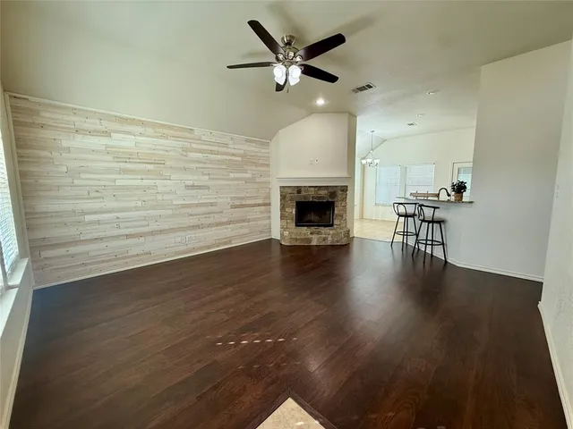 an empty room with wooden floor a fireplace a ceiling fan and wooden floor