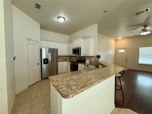 a kitchen with stainless steel appliances granite countertop a sink refrigerator and cabinets