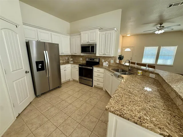 a kitchen with stainless steel appliances granite countertop a refrigerator stove microwave and sink