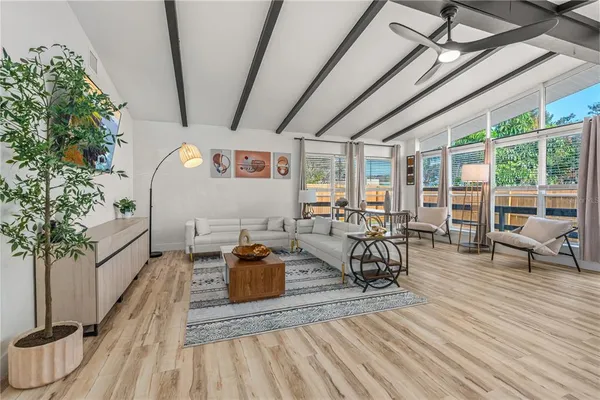 a living room with furniture a dining table with wooden floor and potted plants