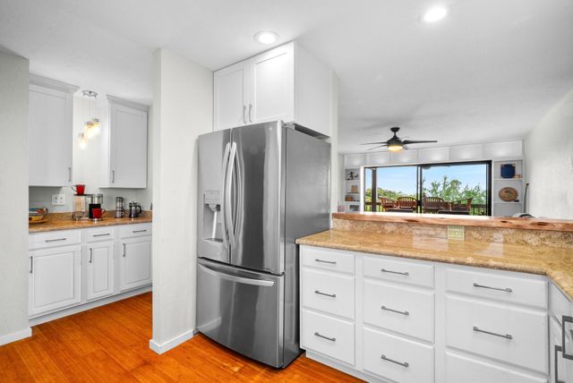 a kitchen with granite countertop white cabinets and stainless steel appliances