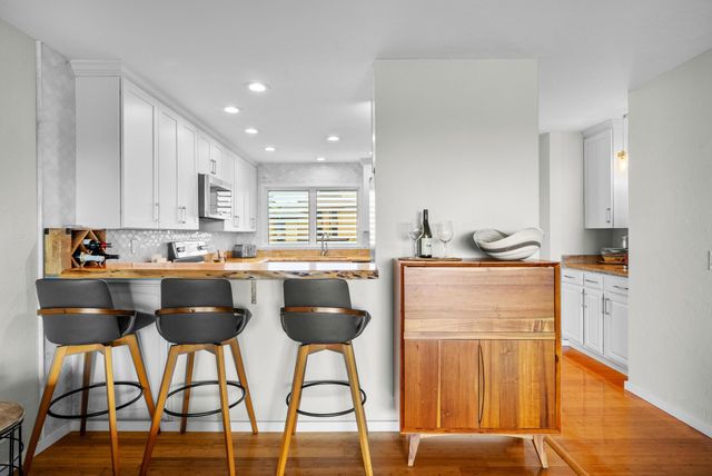 a kitchen with granite countertop a counter space chairs stainless steel appliances and cabinets