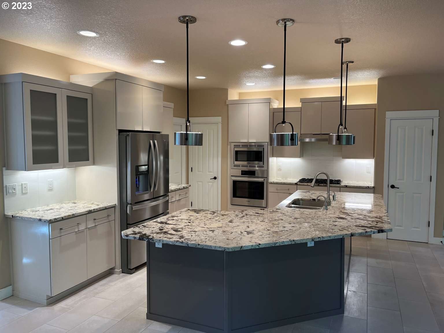 199 Northwest Camp Ireland Street Hillsboro, OR 97124 - Photo 34 of 36 a kitchen with kitchen island granite countertop a sink a counter and refrigerator