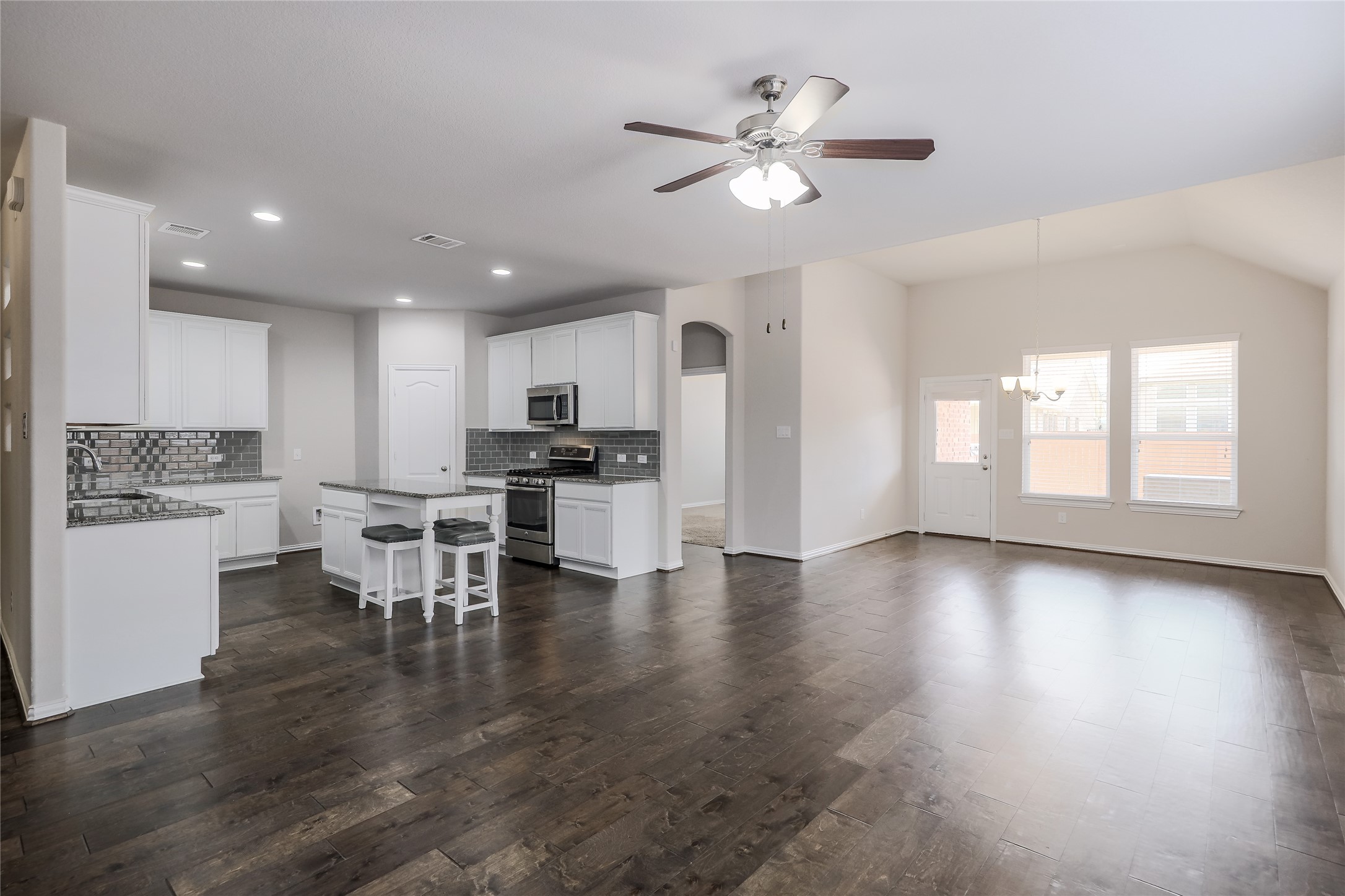 205 Penna Lane Georgetown, TX 78628 - Photo 3 of 32 An open-concept design connects a well-appointed kitchen to a grand living space, boasting vaulted ceilings and gleaming hardwood floors.