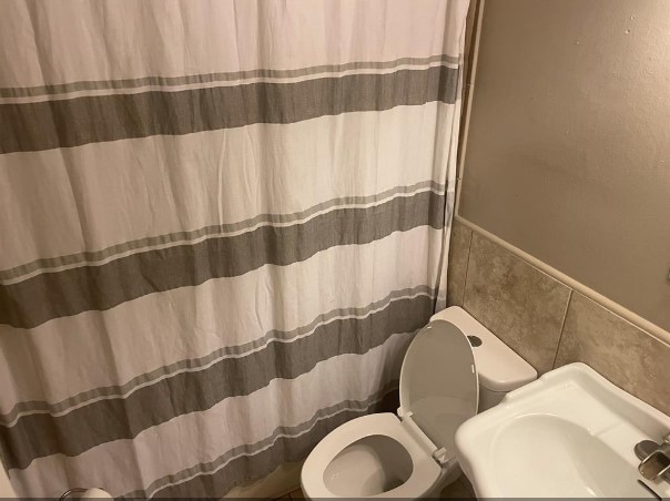 5711 Toddington Road Humble, TX 77346 - Photo 30 of 35 a bathroom with a toilet and a shower curtain