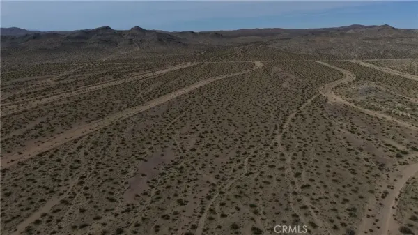 a view of a dry yard with mountains in the background