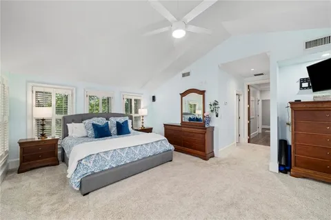 a spacious bedroom with a bed a flat screen tv and dresser