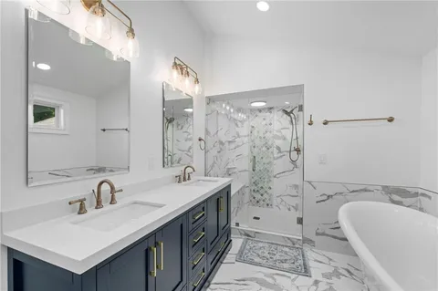 a bathroom with a sink double vanity granite tub shower and a mirror