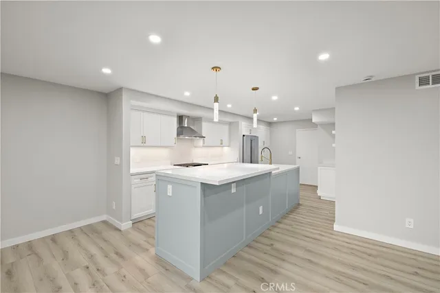 a large kitchen with a large counter top a sink stainless steel appliances and cabinets