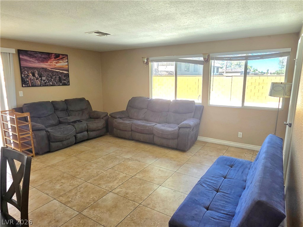 3648 Bronco Road Las Vegas, NV 89103 - Photo 4 of 24 Natural light floods this inviting living space, highlighting its durable tile flooring and relaxed ambiance.
