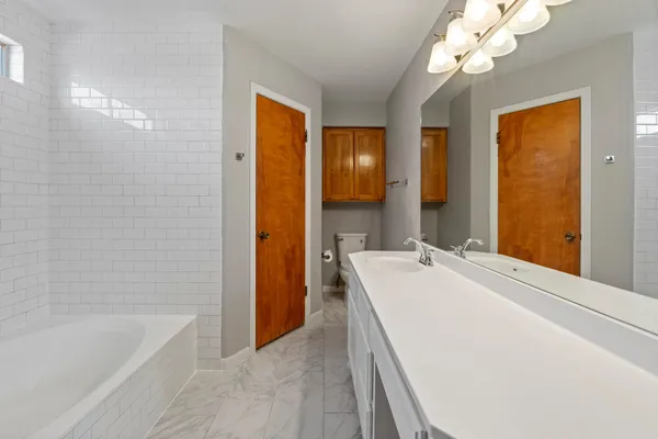 a bathroom with a tub sink and mirror