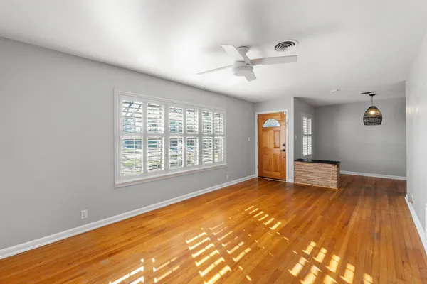 a view of an empty room with wooden floor and a window
