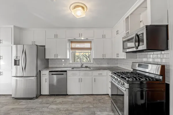 a kitchen with stainless steel appliances granite countertop a stove a sink dishwasher a refrigerator and a microwave