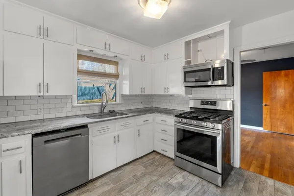 a kitchen with stainless steel appliances granite countertop a stove a sink and a microwave