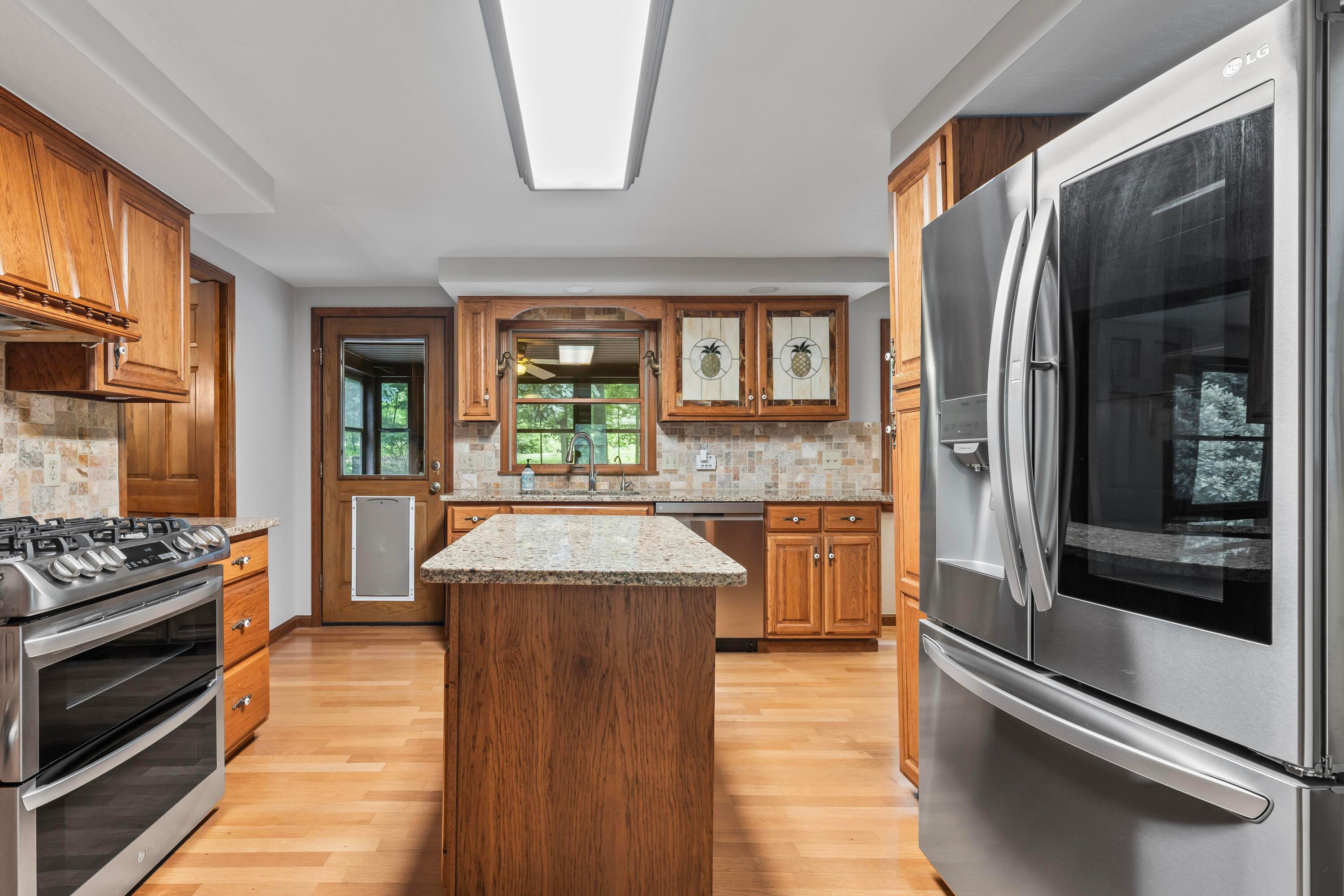 6940 Graham Road Mount Vernon, OH 43050 - Photo 15 of 70 • Hardwood flooring
• Ivory painted walls
• Ceiling light
• Center island with granite
countertops
• Hickory raised panel cabinets
• Wall pantry
• New LG® refrigerator ~ 2021
• New LG® propane gas stove
~ 2021
• LG® dishwasher
• Range hood
• Tumbled marble backsplash
• Double bowl, stainless steel
sink with sprayer & new
faucet
• Door to 3 Season Room