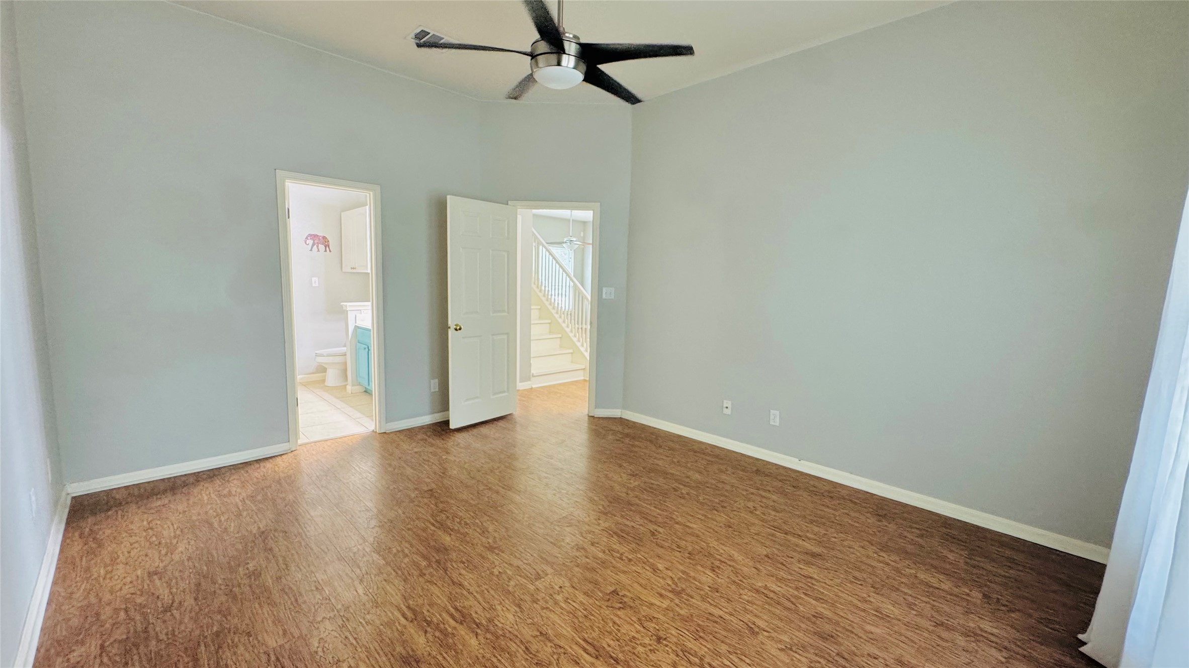 401 Witte Road Kyle, TX 78640 - Photo 8 of 24 Master bedroom-Vast ceilings elevate this airy bedroom, offering rich wood flooring and dual access points.