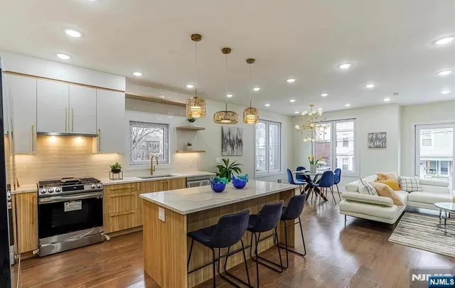 a kitchen with stainless steel appliances kitchen island granite countertop a stove a sink and a dining table with wooden floor