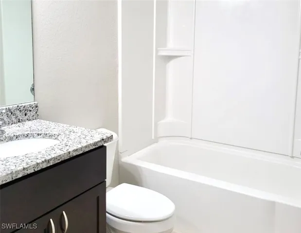 a bathroom with a granite countertop sink toilet and bathtub