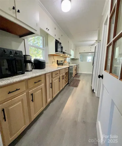 a large kitchen with stainless steel appliances a stove a sink dishwasher and white cabinets with wooden floor