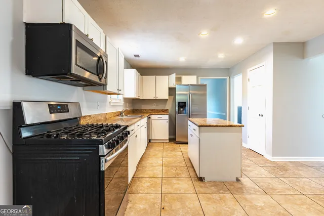 a kitchen with stainless steel appliances granite countertop a stove top oven a sink a counter space and cabinets