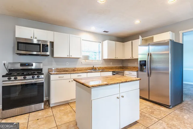 a kitchen with stainless steel appliances granite countertop a stove a sink and a refrigerator