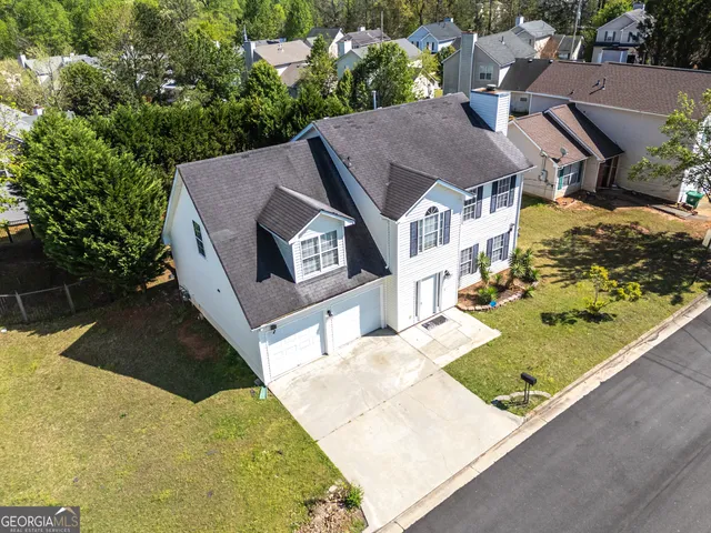 a view of house with yard and trees in the background
