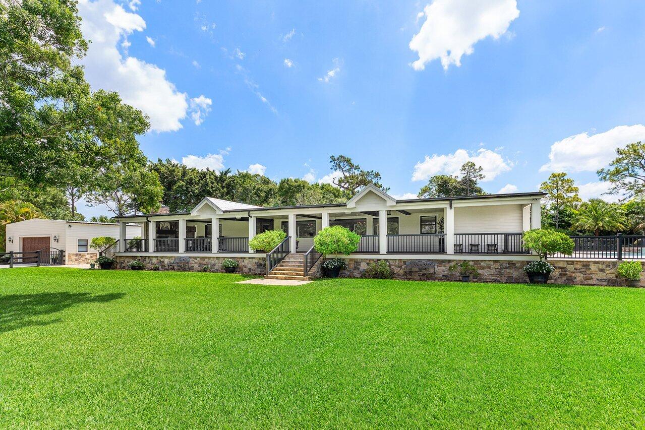 17270 Rocky Pines Road Jupiter, FL 33478 - Photo 3 of 69 a front view of a house with a yard and trees