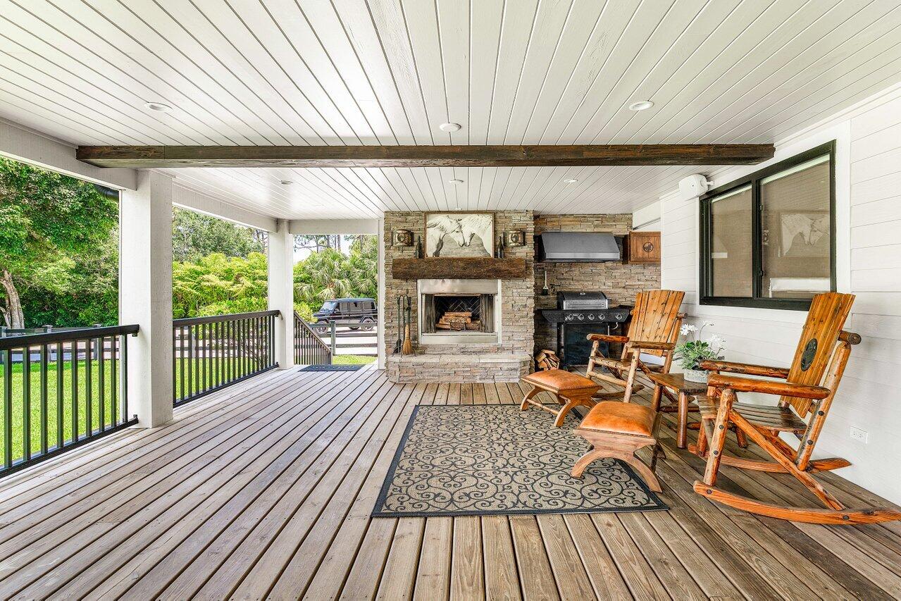 17270 Rocky Pines Road Jupiter, FL 33478 - Photo 9 of 69 a living room with a fireplace furniture a ceiling fan and a large window