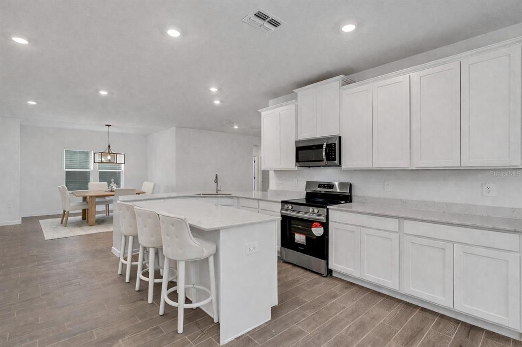 19438 Southwest 79th Street Dunnellon, FL 34432 - Photo 7 of 34 a kitchen with stainless steel appliances kitchen island granite countertop a stove a sink a dining table and chairs