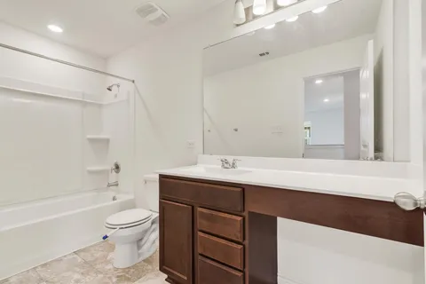 a bathroom with a bathtub shower sink mirror vanity and a toilet