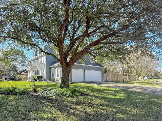 a view of a house with a yard and large tree