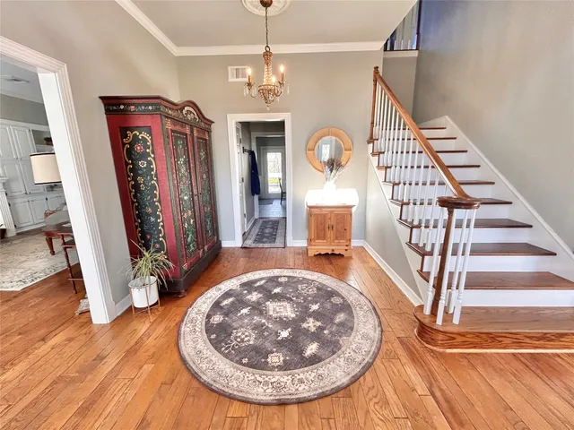 a view of a livingroom with furniture wooden floor staircase and a chandelier