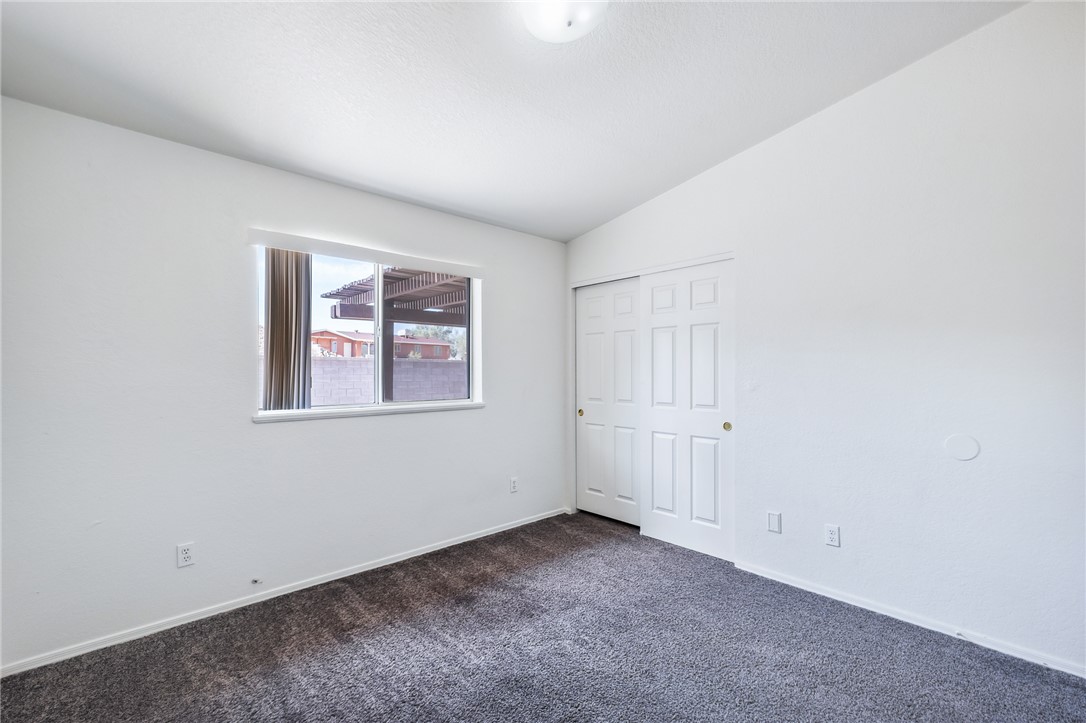 2524 South Ridge Avenue Bullhead City, AZ 86429 - Photo 43 of 64 Unfurnished bedroom with dark colored carpet, lofted ceiling, baseboards, and a closet