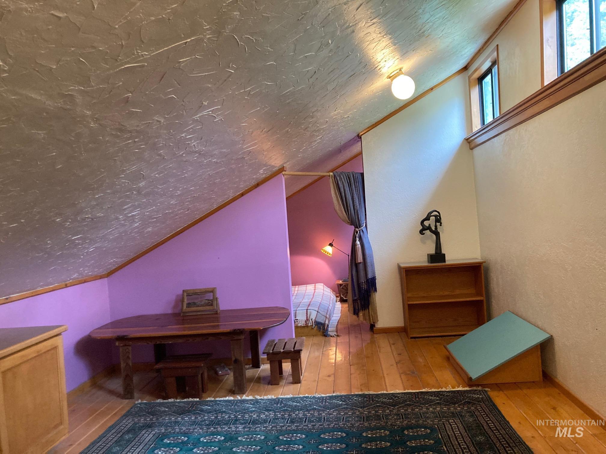 266 Falcon Ridge Road Kooskia, ID 83539 - Photo 20 of 50 Bonus space in loft with wood-finish flooring, accent wall, wood trim, and upper windows