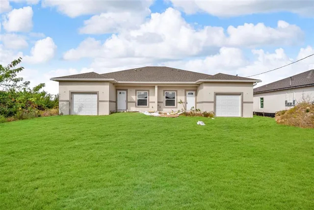 a view of a house with a big yard plants and large trees
