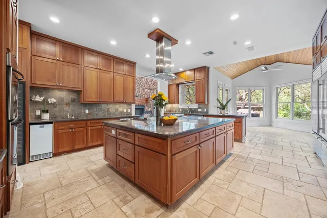 a kitchen with stainless steel appliances granite countertop a kitchen island a stove a refrigerator a sink a dining table and chairs