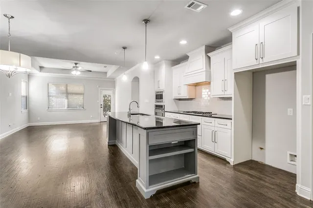 a kitchen with stainless steel appliances granite countertop a stove a refrigerator and a wooden floors