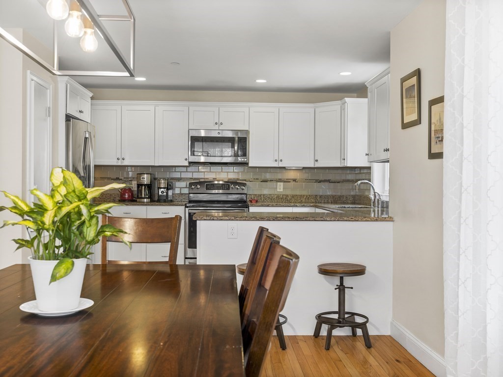 38 Webster Street, Unit 1 Needham, MA 02494 - Photo 8 of 35 a kitchen with stainless steel appliances granite countertop a refrigerator a stove a sink a dining table and chairs with wooden floor