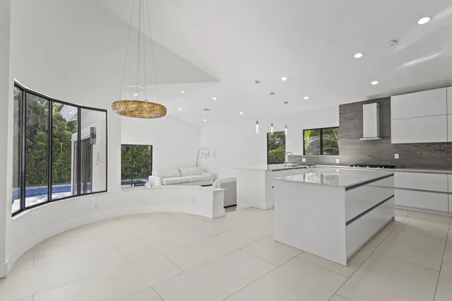 a large white kitchen with a large window and stainless steel appliances